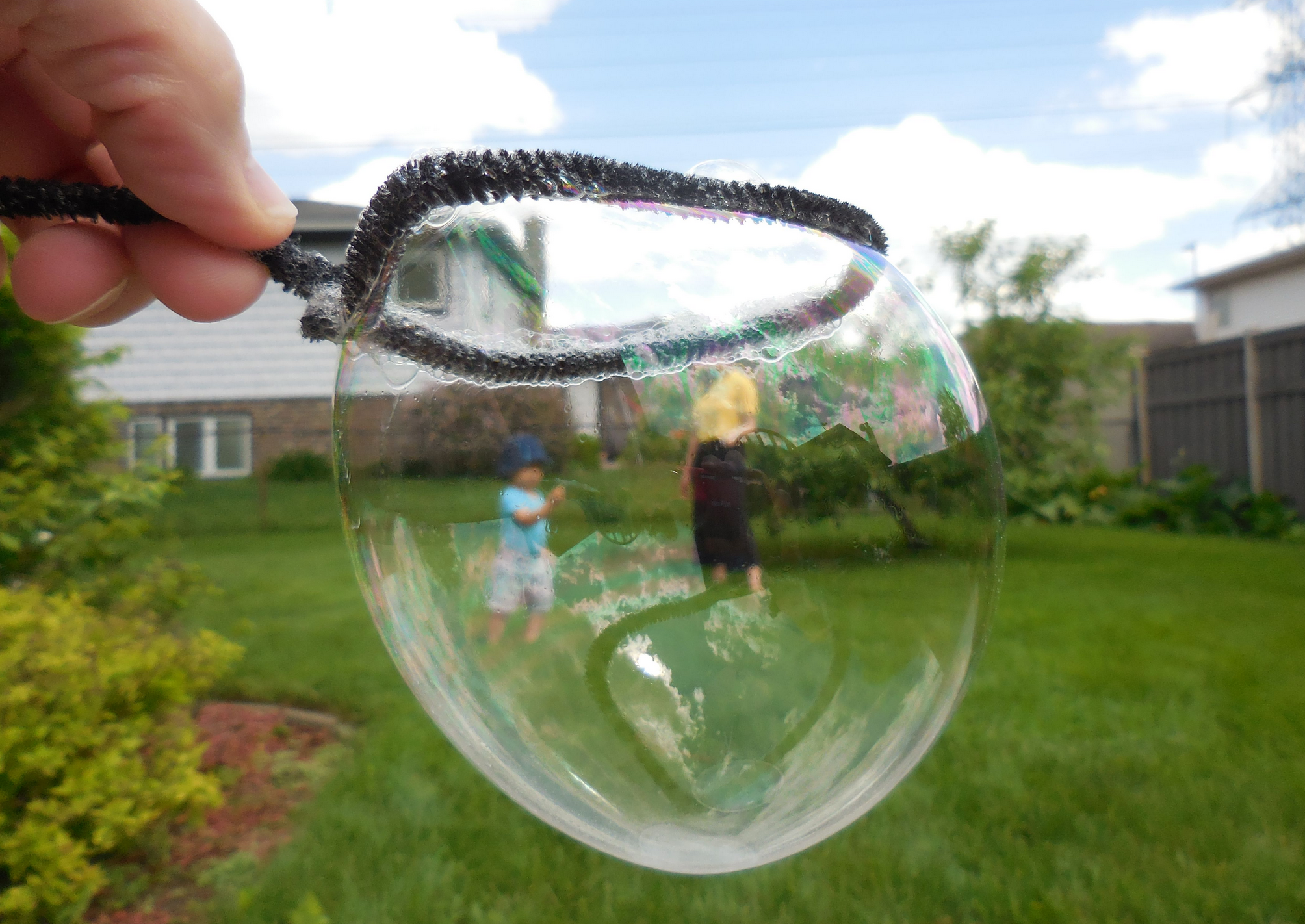 Hand holding bubble wand with bubble in it