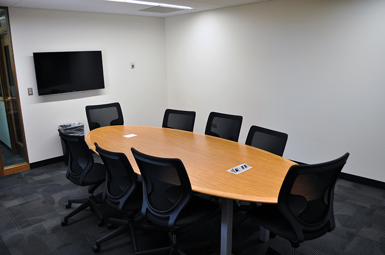room with meeting table, ten chairs, and digital screen